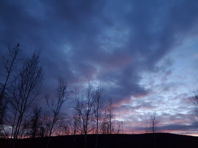 A dark sunset near dusk with dramatic clouds and pink color on the horizon, hints of lighter sky toward the right side of the picture